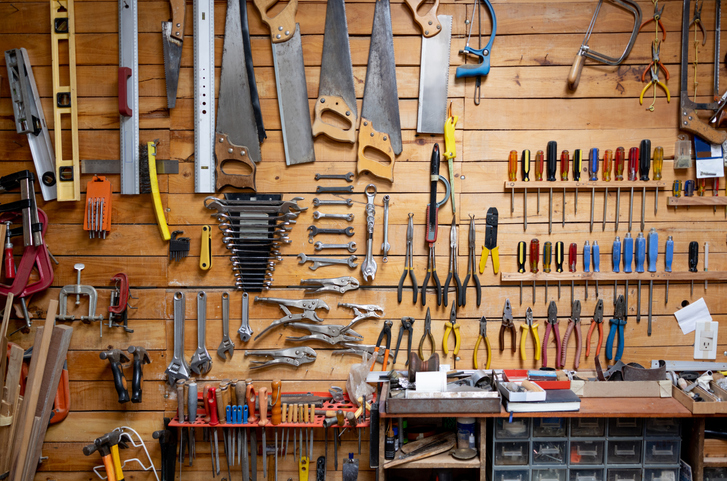 Garage interior with workshop tools hanging on wall.