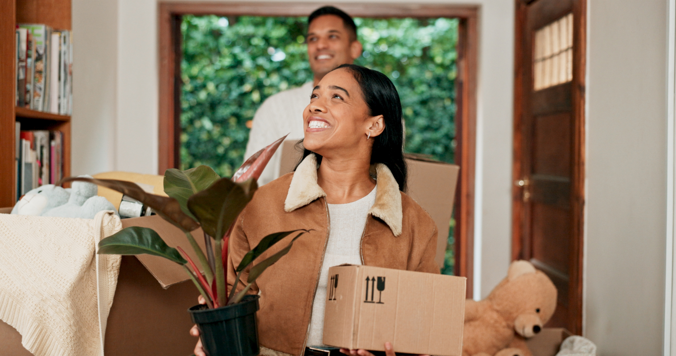 Woman and man with moving boxes and plants entering their dream home