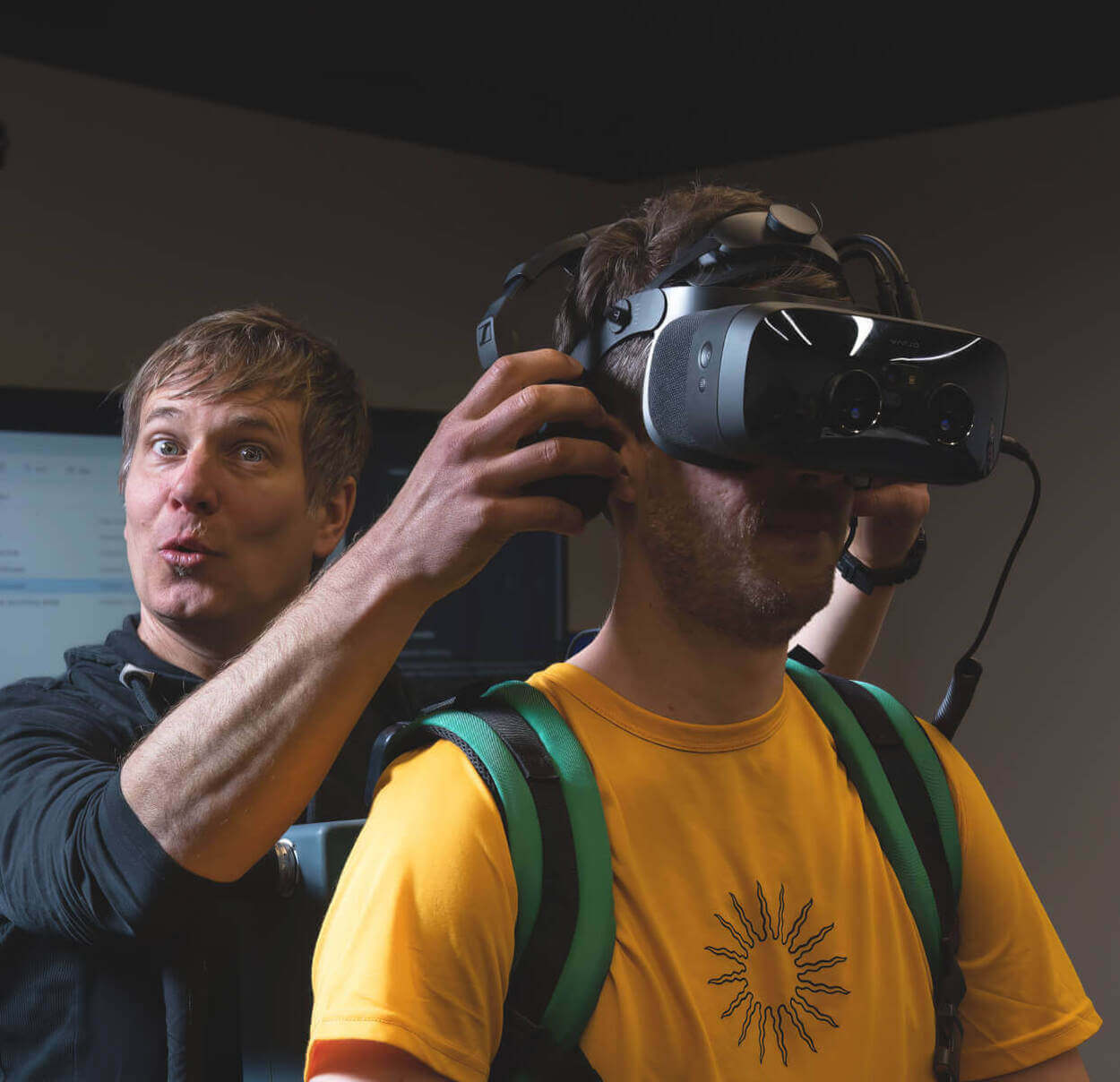 A Lowe's Innovation Labs team member fitting another team member with a VR headset. 