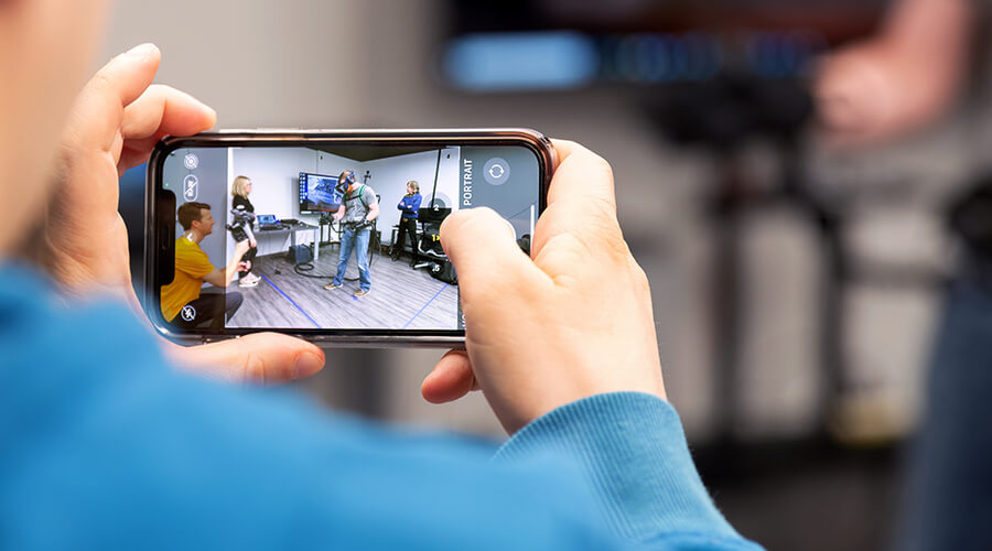 Lowe's Innovation Labs team member filming with their mobile device another team member trying out a VR headset.
