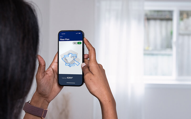 Female measuring bedroom walls with Lowe's Innovation Labs Measure Your Space experience through the Lowe's Home Improvement mobile app.  
