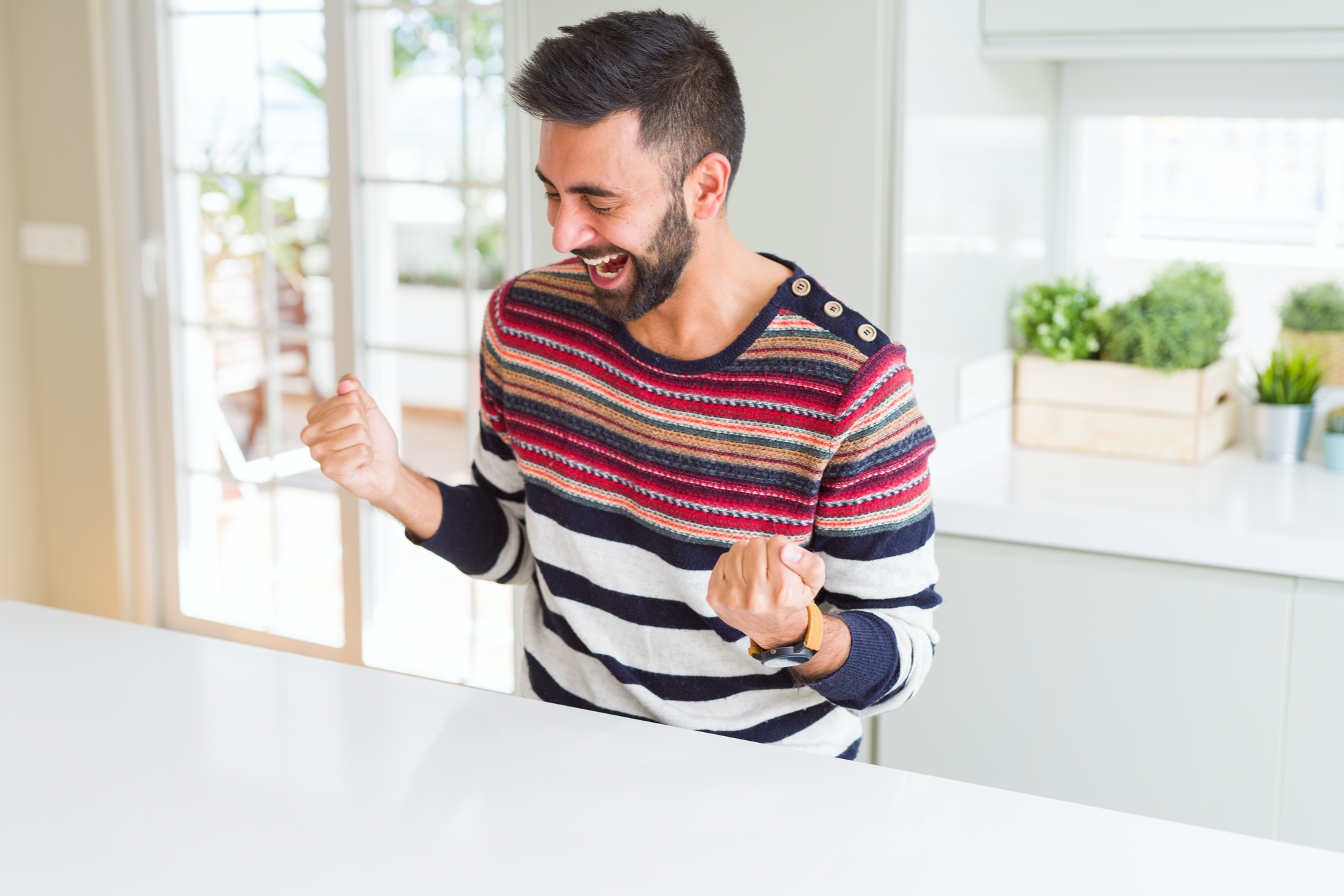 Excited young man in bright, modern kitchen.